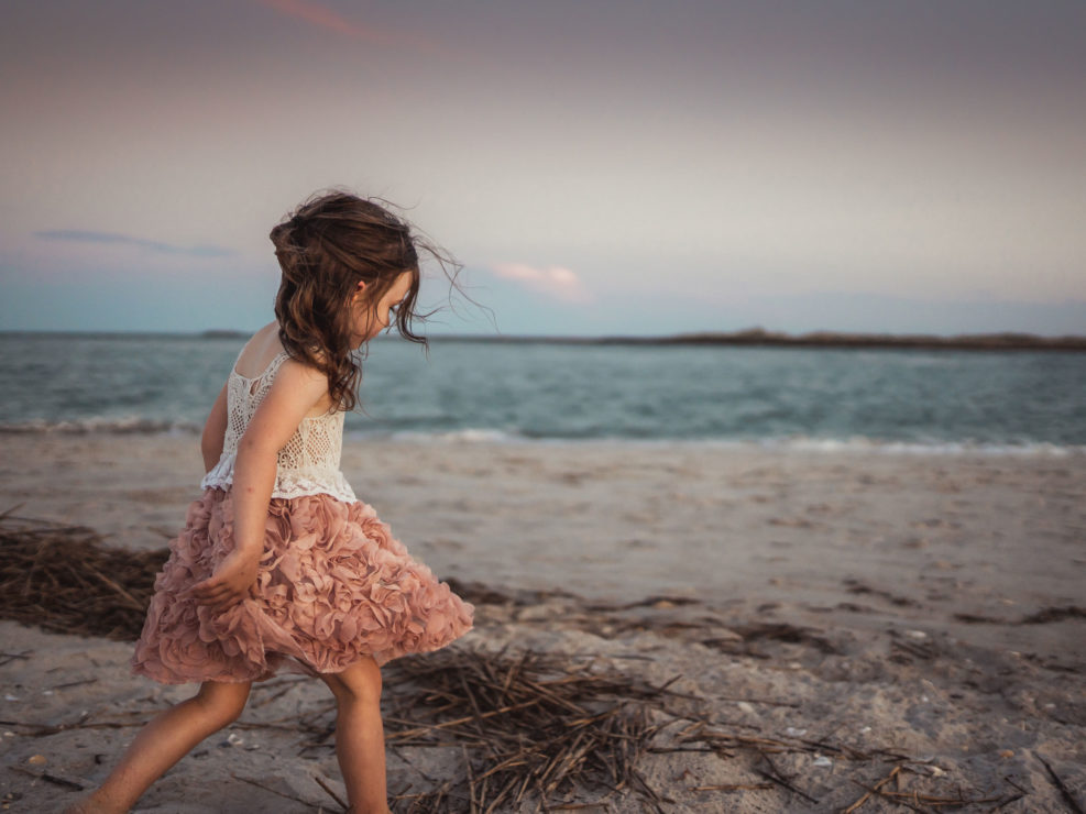 Portrait of a young girl in a dress walking on the beach at Wrightsville Beach captured by Wilmington, NC family photographer Salty Star Photography