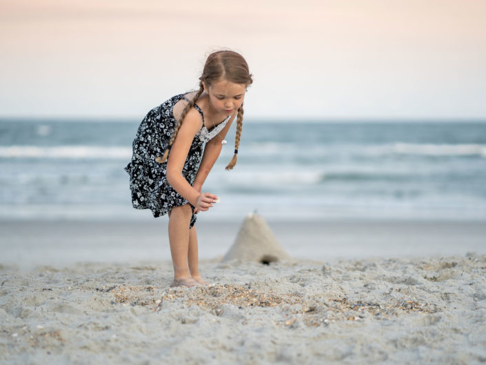 Portrait of a young girl playing in the sand at Wrightsville Beach captured by Wilmington, NC family photographer Salty Star Photography