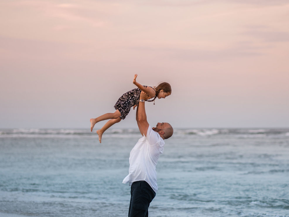 Portrait of a father tossing his daughter in the air in the ocean at Wrightsville Beach captured by Wilmington, NC family photographer Salty Star Photography