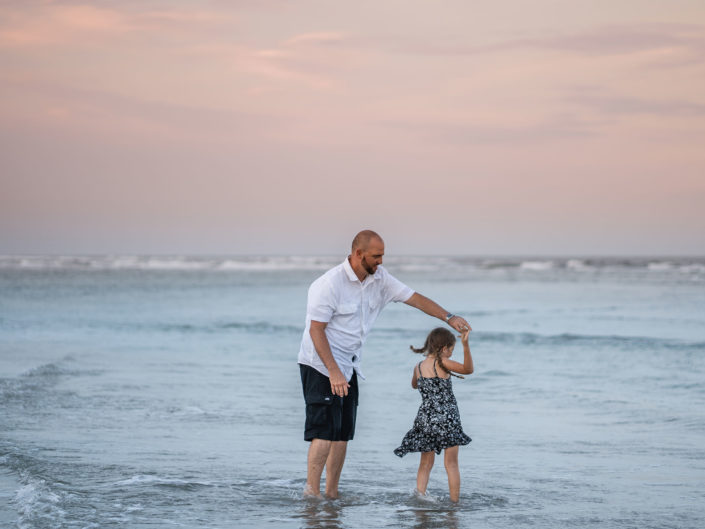 Portrait of a father and daughter dancing in the ocean at Wrightsville Beach captured by Wilmington, NC family photographer Salty Star Photography