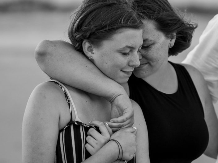 Black and white portrait of a mother and daughter embracing by the ocean at Wrightsville Beach captured by Wilmington, NC family photographer Salty Star Photography