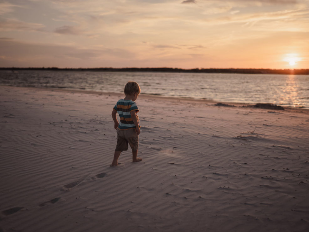Portrait of a young boy walking towards the ocean at Wrightsville Beach captured by Wilmington, NC family photographer Salty Star Photography