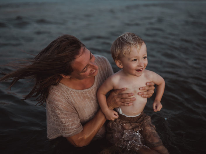 Portrait of a mother and sun playing in the ocean at Wrightsville Beach captured by Wilmington, NC family photographer Salty Star Photography