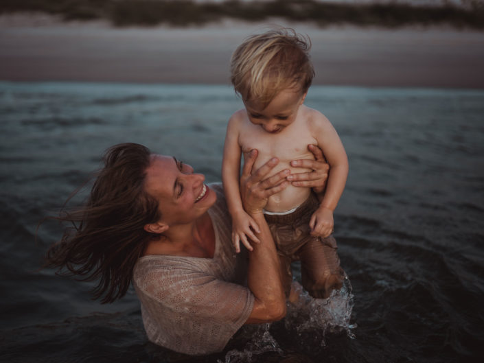 Portrait of a mother and sun playing in the ocean at Wrightsville Beach captured by Wilmington, NC family photographer Salty Star Photography