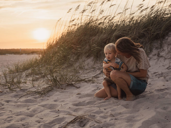 Portrait of a mother and son sitting by a sand dune at Wrightsville Beach captured by Wilmington, NC family photographer Salty Star Photography