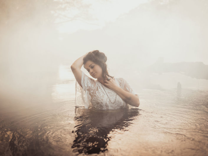 A tattooed woman in a white dress standing in the foggy water at the Black River in Kelly, NC captured by Salty Star Photography