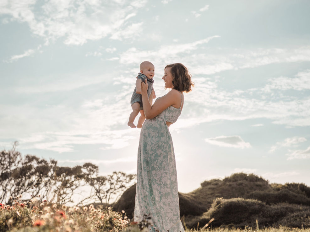 Mother holding her baby son amongst the flowers and oak trees at Fort Fisher, NC captured by Salty Star Photography